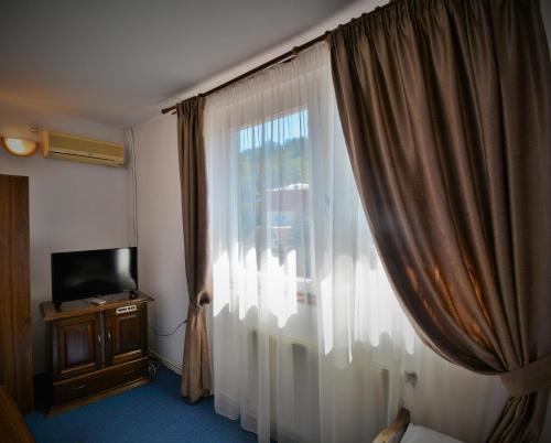 a room with a window with a curtain and a television at Select in Bistriţa