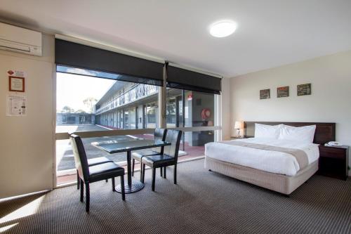 a bedroom with a bed and a table and chairs at Sunshine Motor Inn in Ardeer