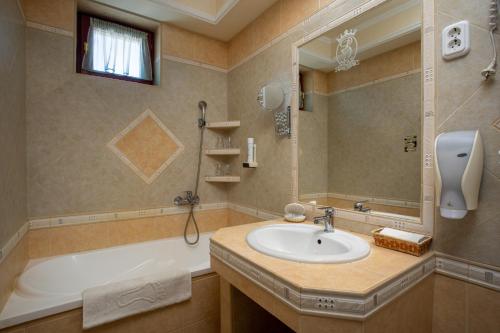 a bathroom with a sink and a tub and a mirror at Illés Hotel in Szeged