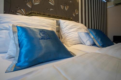 a bed with blue and white pillows on it at Illés Hotel in Szeged