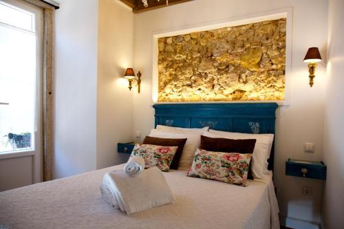 Un dormitorio con una cama con una pared de piedra encima. en Cafofos da Zeta, en Setúbal