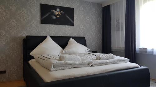 Una cama con mantas blancas y almohadas. en Pension RUBIN, en Bremen