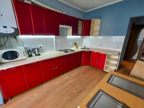 una cucina con armadi rossi e piano di lavoro bianco di Lux.Ap4you.if a Ivano-Frankivsʼk