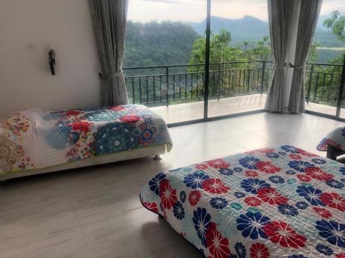 a bedroom with two beds and a balcony with a view at CASA EL MIRADOR in Anapoima