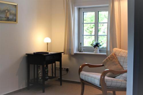 Una habitación con una silla y un escritorio y una ventana. en Föhrer Friesenkate Ost, en Nieblum