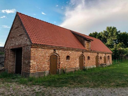 an old brick barn with a red roof at Siedlisko na Wzgórzu in Wizna