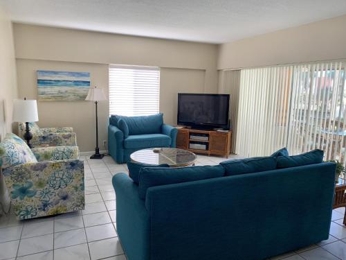 a living room with two blue couches and a television at Island House Beach Resort 12N in Point O'Rocks