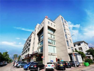a tall white building with cars parked in front of it at Jinjiang Inn Xianju Huancheng North Road in Linhai