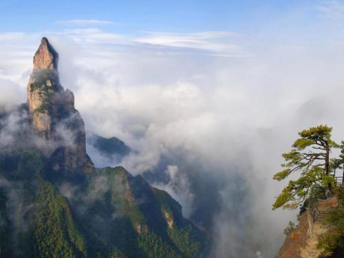 a mountain in the clouds with a tree on it at Jinjiang Inn Xianju Huancheng North Road in Linhai