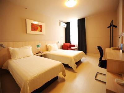 a hotel room with two beds and a chair at Jinjiang Inn Xianju Huancheng North Road in Linhai