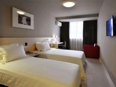 une chambre d'hôtel avec deux lits et une valise rouge dans l'établissement Jinjiang Inn Jiuzhaigou Scenic Resort, à Tazang