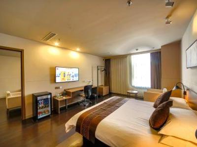a hotel room with a large bed and a television at Jinjiang Inn Select Zibo Boshan Passenger Station Branch in Zibo