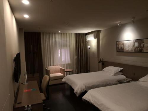 a hotel room with two beds and a chair at Jinjiang Inn Select Jining Huoju South Road Branch in Jining