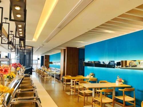 ein Restaurant mit Tischen und Stühlen und einer blauen Wand in der Unterkunft Jinjiang Inn is Qingdao Huangdao Dongjiakou Hotel in Poli