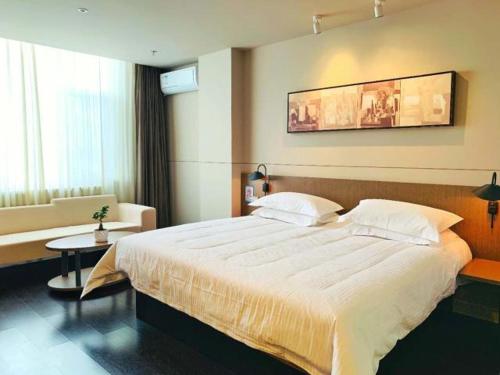 a bedroom with a large bed and a couch at Jinjiang Inn is Qingdao Huangdao Dongjiakou Hotel in Poli