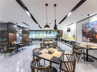 a dining room with tables and chairs in a restaurant at JinJiang InnSelect Suzhou Shengze Shunhuxilu Hotel in Suzhou