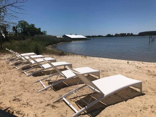 a row of lounge chairs on a beach next to the water at The Quarters at Pier450 in Lexington Park