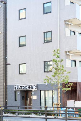 a white building with a sign on it at The Light Inn Tokyo in Tokyo