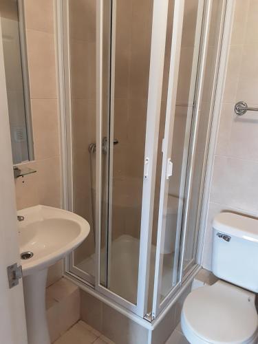 a bathroom with a shower and a toilet and a sink at MaranathaAparthotel in Talcahuano