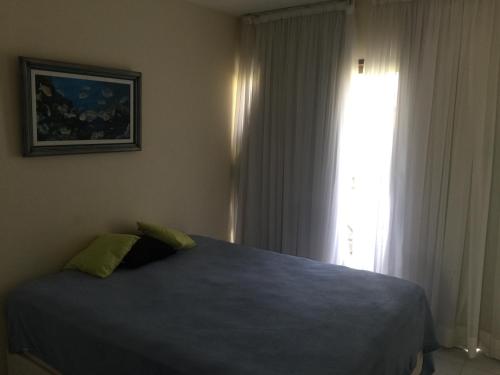 1 dormitorio con cama azul y ventana en Flat Monte Castelo - Gravatá, en Bezerros