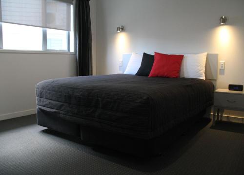 a bedroom with a large bed with a red pillow at Pukekura Motor Lodge in New Plymouth