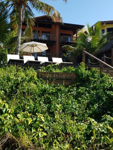 a bench with an umbrella in front of a building at Pousada Pedra da Gaivota in Bombinhas