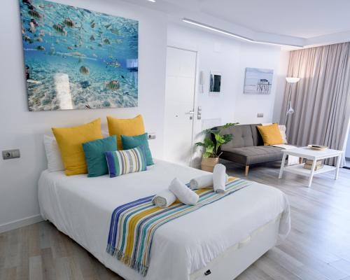 ein weißes Schlafzimmer mit einem großen Bett mit bunten Kissen in der Unterkunft CANARIAN HOLIDAY HOME - Guest House Gran Canaria in San Bartolomé de Tirajana