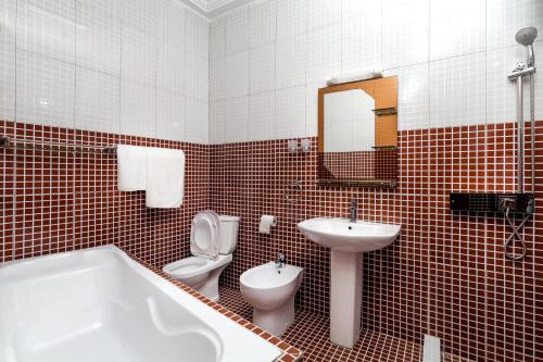 a bathroom with a tub and a toilet and a sink at Hotel BKBG in Lomé