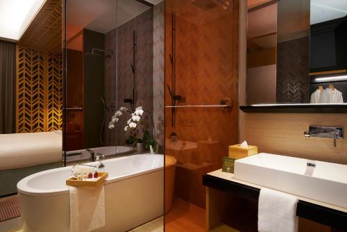 a bathroom with a tub and a sink at Oasia Hotel Downtown, Singapore by Far East Hospitality in Singapore