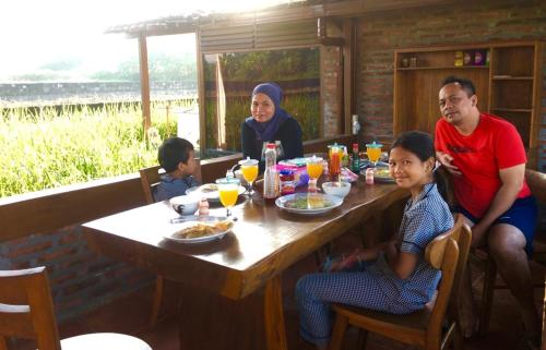 a group of people sitting at a table eating food at Alamanda Family Villas, Pool & Local Tours in Yogyakarta