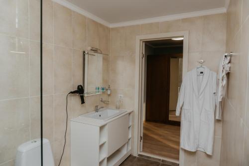 La salle de bains blanche est pourvue d'un lavabo et d'une douche. dans l'établissement Aral Hotel, à Aralʼsk