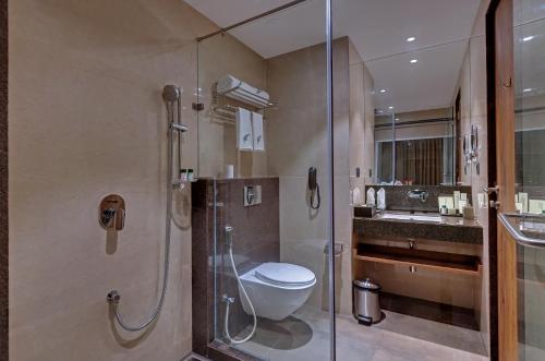 a bathroom with a toilet and a shower and a sink at The Fern Royal Farm Resort, Anjar in Anjār