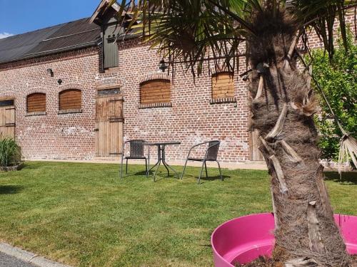 a table and chairs in a yard next to a building at Le petit manoir d'Hebuterne in Hébuterne
