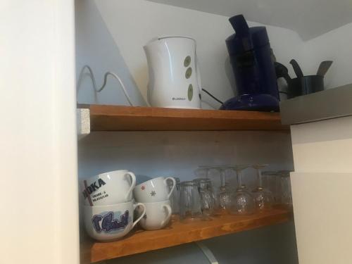 une étagère avec des tasses et d'autres articles en verre dans l'établissement Le petit manoir d'Hebuterne, à Hébuterne