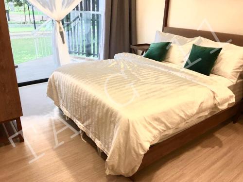 uma cama com lençóis brancos e almofadas verdes num quarto em TA-G-11 @timurbay em Kuantan