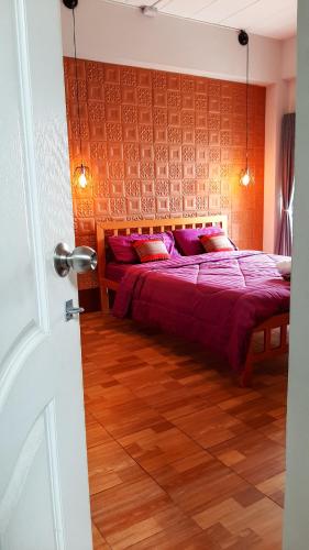 a bedroom with a bed with purple sheets and red pillows at Pranot Apartment & Spa in Nonthaburi