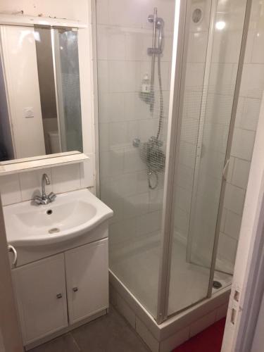 une salle de bain blanche avec une douche et un lavabo dans l'établissement Nid Calme Nord Paris, à Pierrefitte-sur-Seine