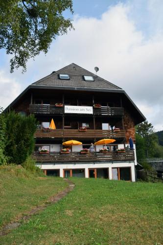 a building with tables and umbrellas in front of it at FeWo Am See in Schluchsee