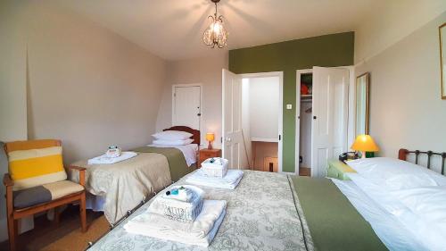 1 dormitorio pequeño con 2 camas y 1 silla en Muswell Hill B&B en Londres