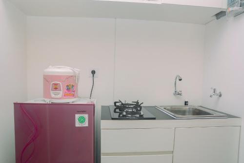 eine Küche mit einem rosa Gerät auf einem Kühlschrank in der Unterkunft New Furnished Studio Grand Kamala Lagoon Apartment By Travelio in Pekayon Satu