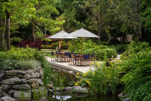 a patio with tables and umbrellas next to a pond at New World Qingyuan Hotel -formerly KHOS QINGYUAN in Qingyuan