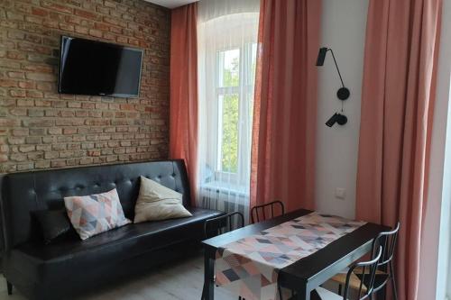 sala de estar con sofá negro y mesa en Apartament w kamienicy Przy Plantach, en Kalisz