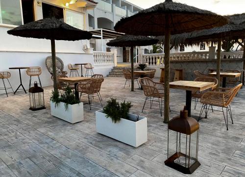 an outdoor patio with tables and chairs and umbrellas at ICON Valparaiso - Adults Only in Cala Murada