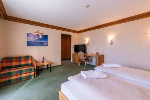 une chambre d'hôtel avec deux lits et un canapé dans l'établissement SCOL Sporthotel Zillertal, à Fügen