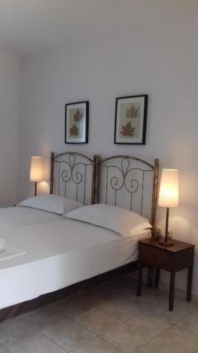 two beds in a bedroom with two lamps on a table at Aegean Blue Studios in Afitos