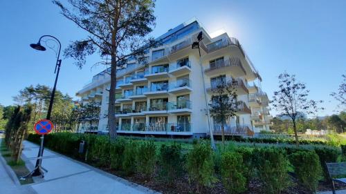 ein weißes Apartmenthaus mit einem Baum davor in der Unterkunft ApartPark Apartament Albus in Świnoujście