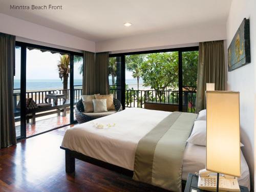 a bedroom with a bed and a balcony with the ocean at Praseban Resort in Pran Buri