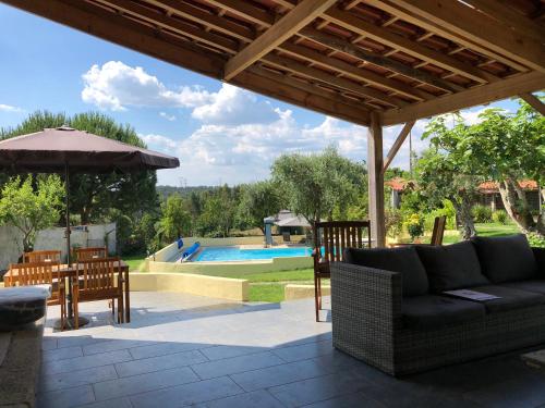 a patio with a couch and an umbrella and a pool at A Casa Amarela in Pinheiro de Coja