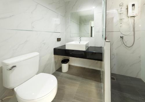 a white bathroom with a toilet and a sink at B Hotel in Khon Kaen