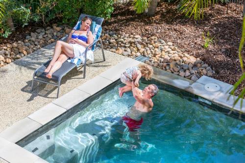 a woman and two children playing in a swimming pool at RACV Noosa Resort in Noosa Heads
